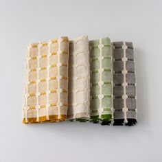 four different colored towels are lined up on a white surface, one is green and the other is yellow