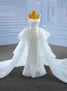 a white wedding dress on display in front of a mannequin headdress