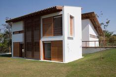 a white house with wooden slats on the roof and side walls, in front of a grassy area