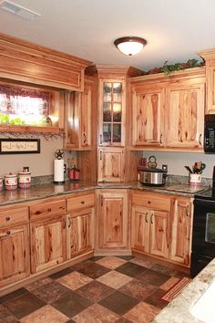 a kitchen with wooden cabinets and black stove top oven in the center, surrounded by tile flooring