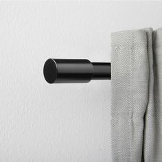 a black curtain is hanging on the side of a white wall with a round rod