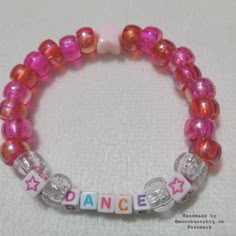 a close up of a beaded bracelet on a white surface with the word dance spelled in small letters