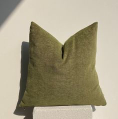 a green pillow sitting on top of a white block