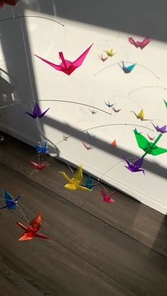 a hand holding a string with colorful origami birds hanging from it's side