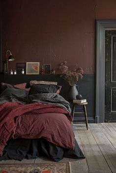 a bedroom with dark red walls and wooden floors