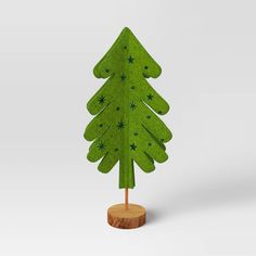 a small green christmas tree sitting on top of a wooden stand