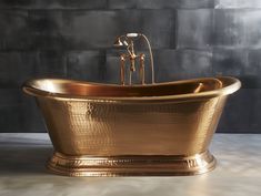 a gold bathtub with two faucets on the front and side, against a gray wall