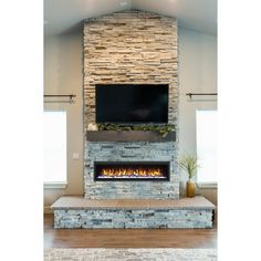 a living room with a large stone fireplace and flat screen tv mounted on the wall