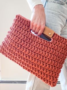 a person holding a crocheted purse with a cell phone in it's pocket