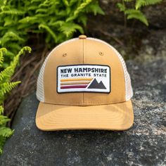 -Embroidered New Hampshire patch -6 Panel Structured Cap -Slightly Curved Brim Visor -Mid Height Crown -Plastic snapback closure Free Shipping on all Hats Brown Baseball Cap Trucker Hat For Hiking, Brown Trucker Hat For Hiking, Camping Hat With Curved Brim And Logo Patch, Camp Merch, Camping Snapback Baseball Cap With Logo Patch, Six-panel Baseball Cap With Logo Patch For Outdoors, Outdoors Style, Hat Patch, Hat Patches