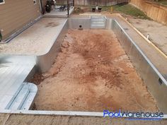 an empty pool in the middle of a yard with dirt on the ground and two men working