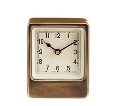 a small square clock with numbers on the front and sides is shown in gold, against a white background