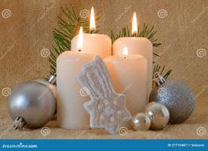 three candles with christmas decorations and baubles on a burlock cloth background