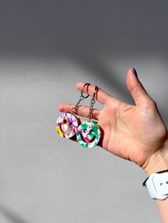 a person's hand is holding two rings in the shape of donuts on a chain