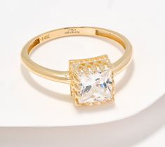 a gold ring with a square cut diamond in the center on a white surface,