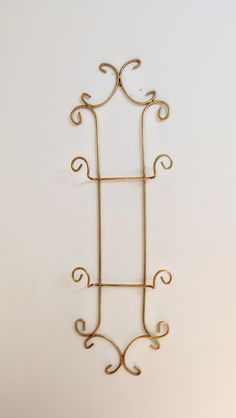 a metal wall hanging on the side of a white wall with an iron frame and scroll design