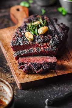 sliced steak on a cutting board with garnish and seasoning sprinkles