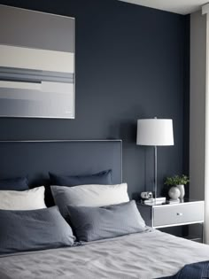 a bedroom with blue walls and grey bedding, two nightstands and a painting on the wall