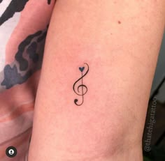 a small musical note tattoo on the right arm and shoulder, with a heart in the middle