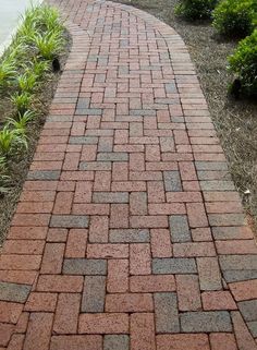 a red brick walkway with grass and bushes