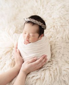 a newborn baby wrapped in a blanket is being held by a woman's hands