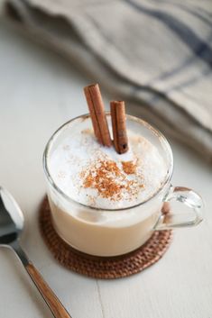 two cinnamon sticks sticking out of the top of a mug filled with coffee and cream