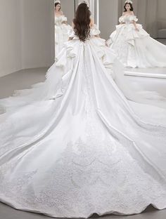 a woman in a white wedding dress is looking at herself in the mirror with her back to the camera