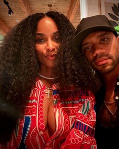 a man standing next to a woman in a red and white dress with long curly hair