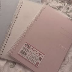 three notebooks sitting next to each other on top of a bed covered in sheets