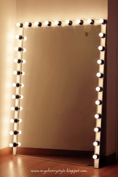 a mirror that has lights on it and is next to a wall with a light up frame