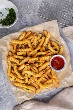 some fries are on a plate with ketchup and sauce next to the basket