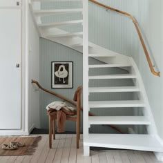 there is a white stair case in this room with wood flooring and striped walls