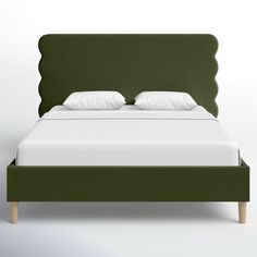 a bed with green headboard and white pillows on it's sides, in front of a wall