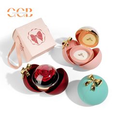 three small round boxes with bows on the top and one containing a perfume bottle in it