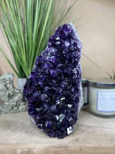 a purple rock sitting on top of a wooden table next to a potted plant