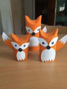 four little foxes made out of toilet paper sitting on a wooden table next to each other