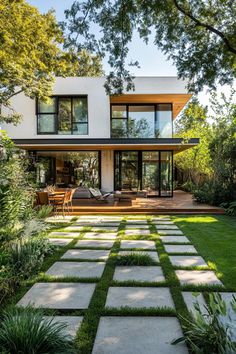 a modern house in the middle of a lush green yard with grass and stepping stones