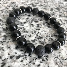 Onyx And Lava Stone 10mm Beaded Bracelet w/ Silver Accents This right here is an Embody'd Art Favorite! A great casual black beaded piece made for every occasion. The silver accents add a hint of luster and shine. And this piece will surely draw attention to you wrist! Can be stacked or worn separately or stacked with other pieces. This bracelet is crafted with quality elastic stretch cord. This bracelet is also designed to fit snug on the wrist. Laced 4 times to ensure maximum strength and hold Casual 8mm Round Beads Jewelry, Casual Round 8mm Beads Jewelry, Gift Round Black Beaded Bracelets, Black Beaded Bracelets For Healing With 8mm Beads, Onyx Beaded Bracelets As Gift, Black Spiritual Beaded Bracelets With Polished Beads, Healing Black Beaded Bracelets, Minimalist Black Beads For Gifts, Minimalist Black Beads For Gift