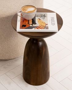 a cup of coffee sitting on top of a wooden table next to a magazine holder