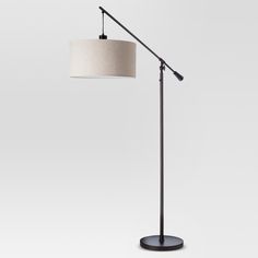 a floor lamp with a white shade on it's head and a black base