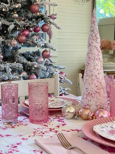 the table is set for christmas dinner with pink and silver decorations