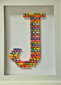 the letter j made out of crayons is in a white framed box frame