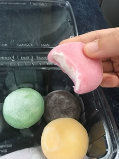 a hand is picking up some kind of doughnut from a plastic container on the table