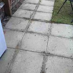 a small white refrigerator freezer sitting on top of a cement floor next to a lawn