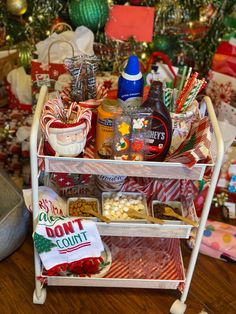 a cart filled with lots of holiday food and condiments next to a christmas tree