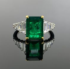 The vivid green of the emerald exudes timeless allure, while the surrounding diamonds add a touch of dazzling brilliance. Whether it's a special occasion or an everyday statement, this exquisite piece is a reflection of your refined taste and a cherished addition to your jewelry collection. Details: 18K Gold: 4.63 grams  Diamond - 0.78 Ctw Emerald - 3.13 Cts Luxury Green Rings With Diamond Accents, Luxury Emerald Birthstone Ring, Luxury Green Diamond Ring, Green Diamond Ring For Formal Occasions, Luxury Emerald Ring For May Birthstone, Luxury Tsavorite Emerald Ring For Formal Occasions, Exquisite Green Diamond Ring With Brilliant Cut, Exquisite Green Diamond Ring With Accents, Dazzling Green Diamond Ring For Formal Occasions