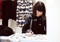 a woman is sitting at a table in front of a display of clothing and accessories