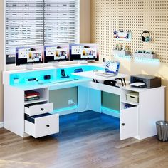 an office desk with two computers on it and blue lighting underneath the desk is a trash can