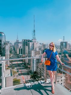 a woman standing on top of a metal railing in front of a cityscape