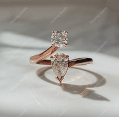 two pear shaped diamond engagement rings sitting on top of each other